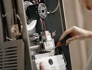 Furnace repair technician inspecting internal components and wiring in Salt Lake City, UT