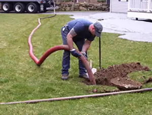 Septic pumping technician servicing a residential septic tank with a vacuum hose in Salt Lake City, UT