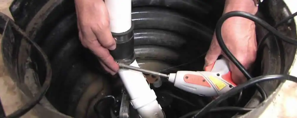 Sump pump installation technician connecting PVC discharge piping in Salt Lake City, UT