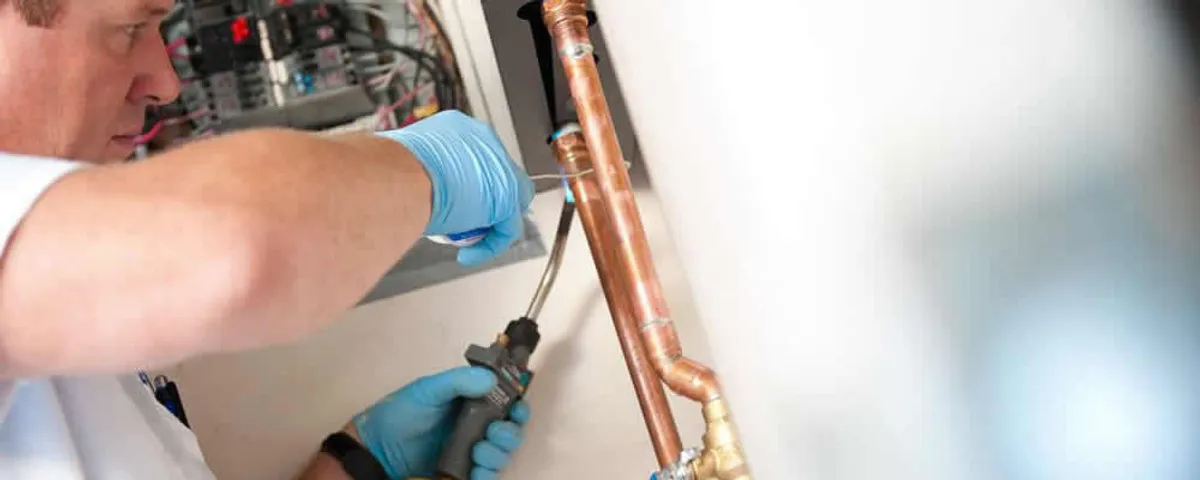 Water heater repair technician testing copper pipe connections and controls in Salt Lake City, UT