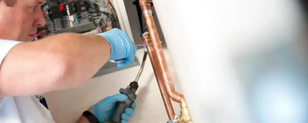 Water heater repair technician testing copper pipe connections and controls in Salt Lake City, UT